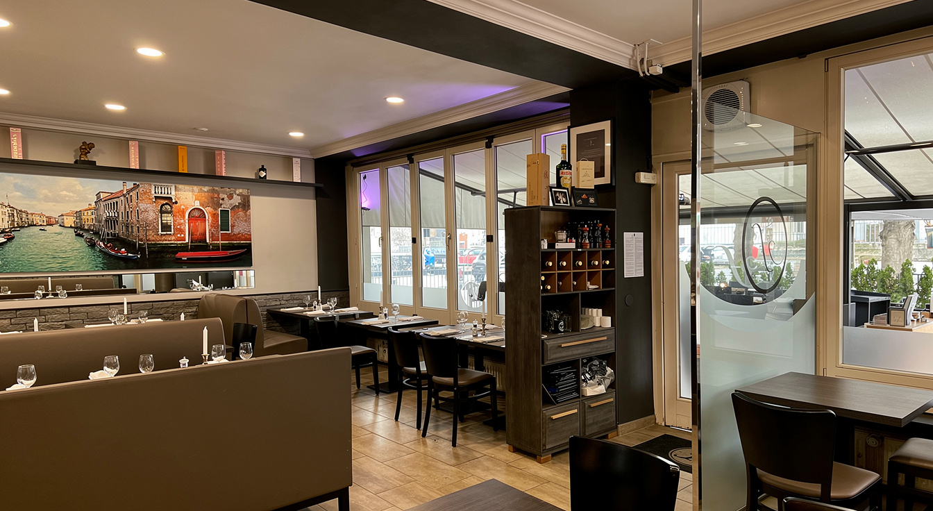 Der Gastraum des Ristorante Farinelli bei Kerzenlicht, mit den großformatigen Venedig-Wandbildern und dem dunklen Weinregal