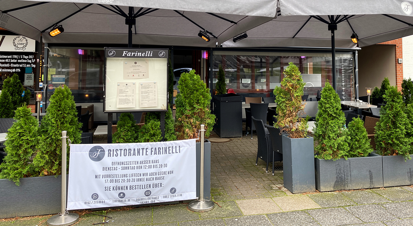 Die überdachte Terrasse vor dem Ristorante Farinelli am Hofweg mit Heckenpflanzen und dem Farinelli-Schild
