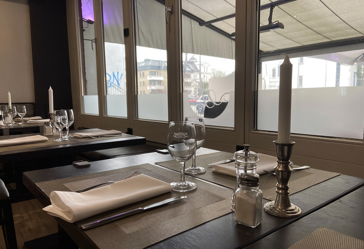 Gedeckter Fenstertisch mit weißem Leinen, Weingläsern und einem silbernen Kerzenleuchter